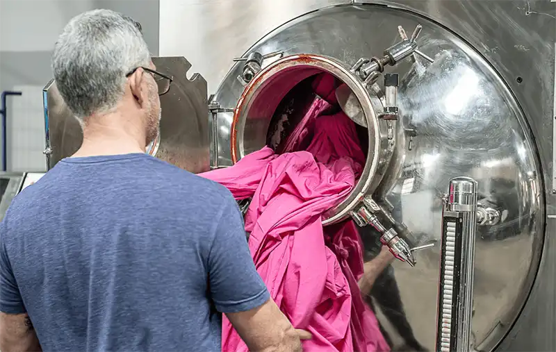 Person loading a pink garment into a machine to be washed