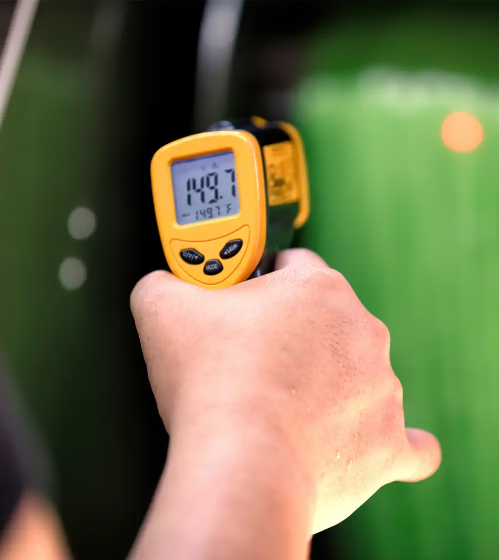 Person holding an infrared thermometer checking the temperature of a green fabric being dyed